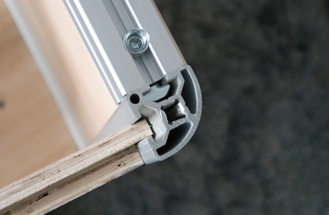 One of the aluminium extrusions viewed end-on. A rabbet on the side of a plywood panel slots into it.