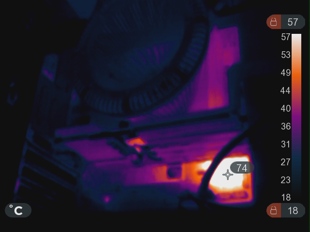 An infra-red image of the inside of a computer. Most of it looks cool, except a patch in the lower right of the motherboard at 74°C.
