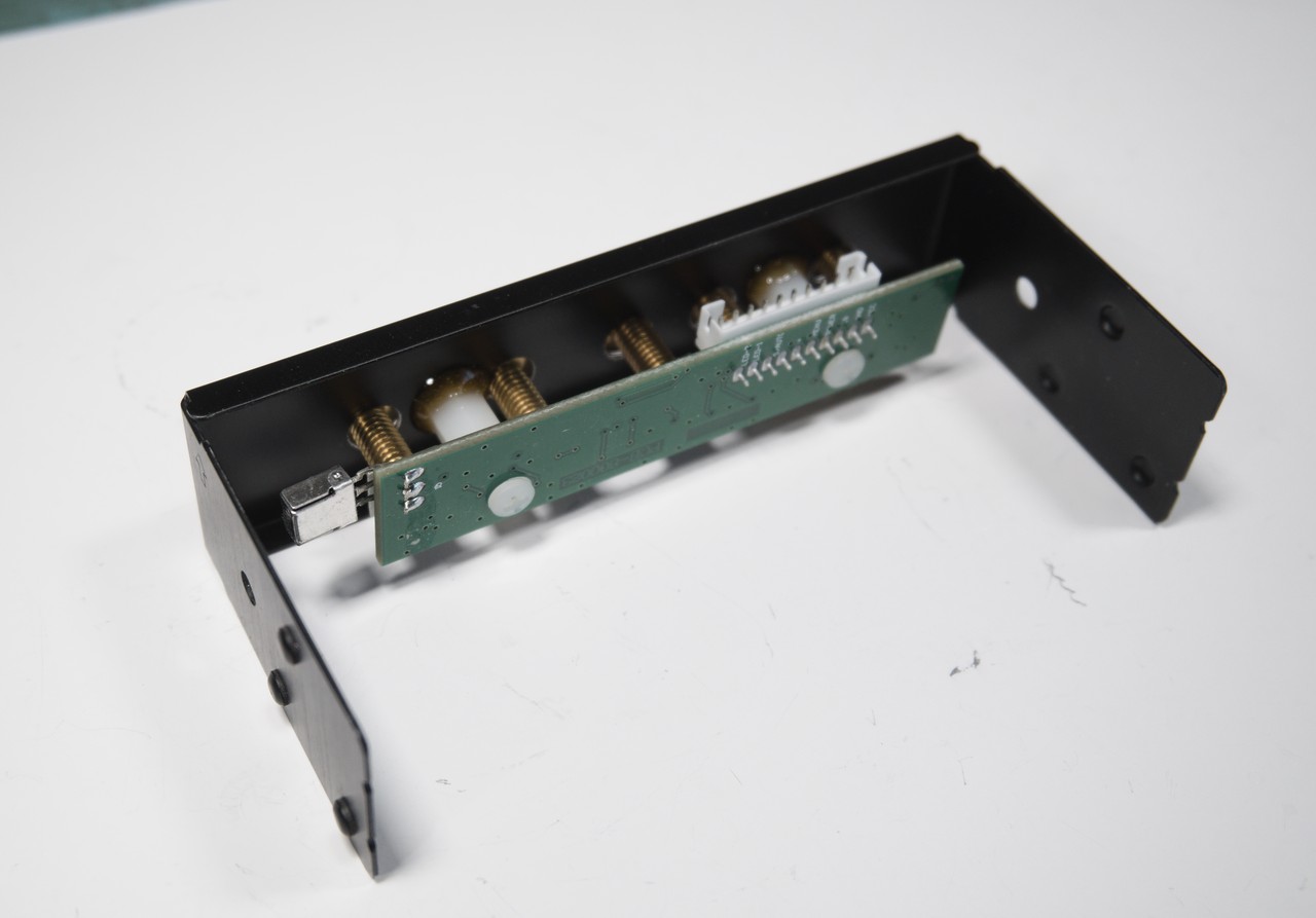 Rear view of a drive bay cover with the switch PCB mounted to it.