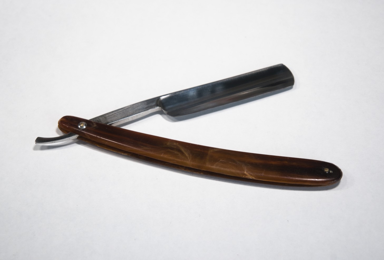 A straight razor slightly unfolded to show the cutting edge.
