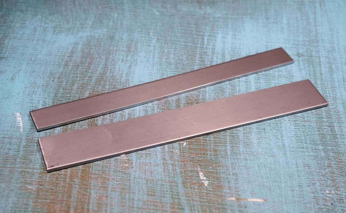 The same titanium plate, cut lengthwise into one larger and one smaller strip.