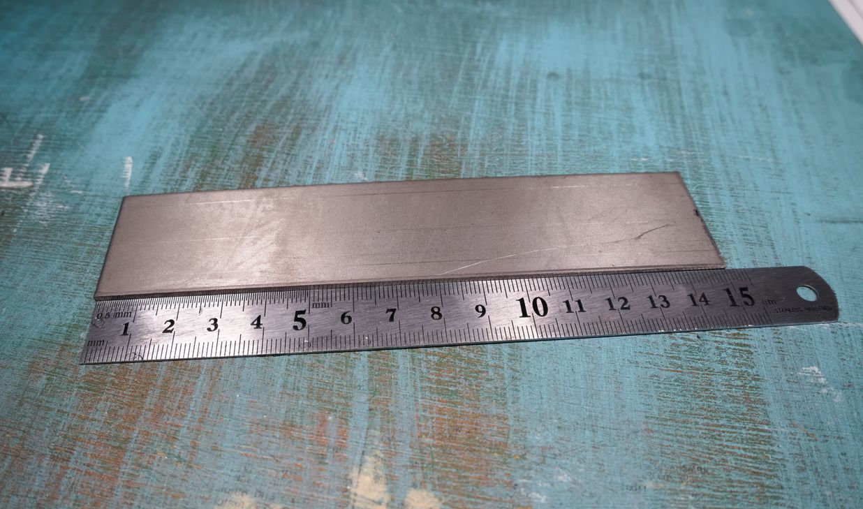 A small titanium plate, with a ruler next to it showing that it's 150mm long.